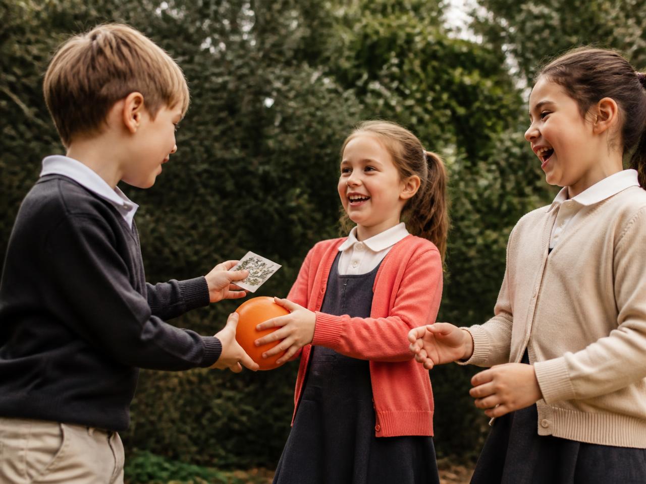 Trois enfants debout se passant une balle et une carte pédagogique